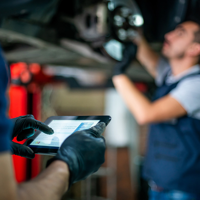 Mechanic holding a tablet checking the readings of the car's inspection