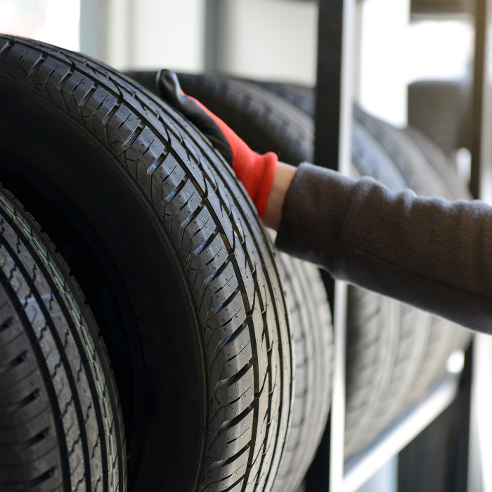 Male mechanic holding tire while repairing service