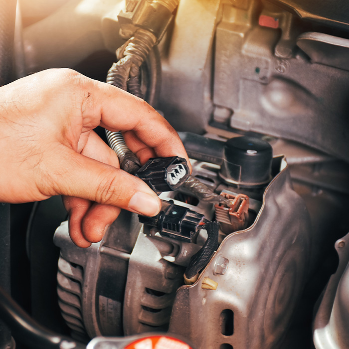 The auto mechanic hand is grasping the car alternator charger plug