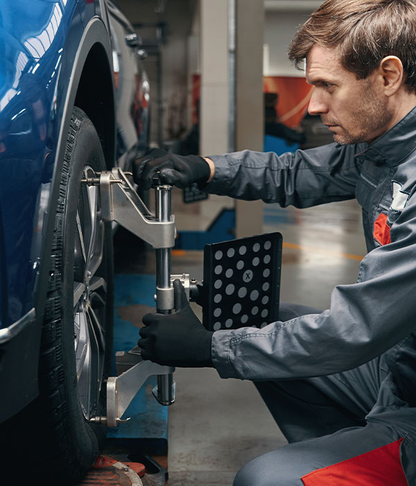 Mechanic inspecting wheel alignment in the workshop
