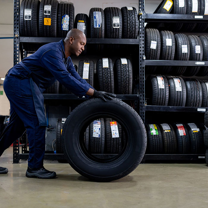 Mechanic changing a flat tire and carrying a wheel at a repair garage