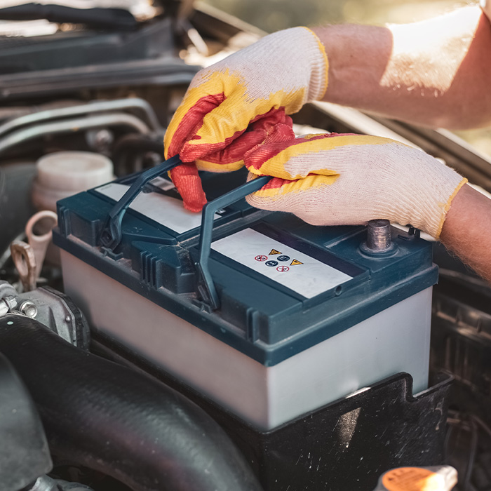 Mechanic removing a car battery from the box.
