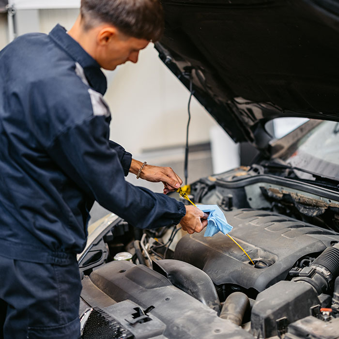 Mechanic checking an engine oil on a car