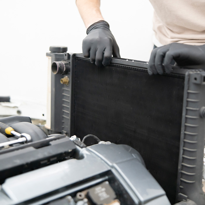 Car mechanic installing new radiator in a vehicle