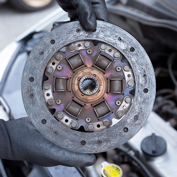 Mechanic wearing protective work gloves holds old clutch disc